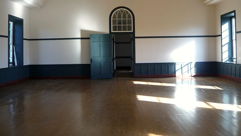 A closed wooden door with a small frosted glass panel at the end of a carpeted corridor in a residential building