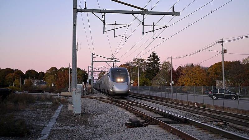 A worn dirt footpath crossing a set of tracks between two fences, with gravel ballast scattered across the ties