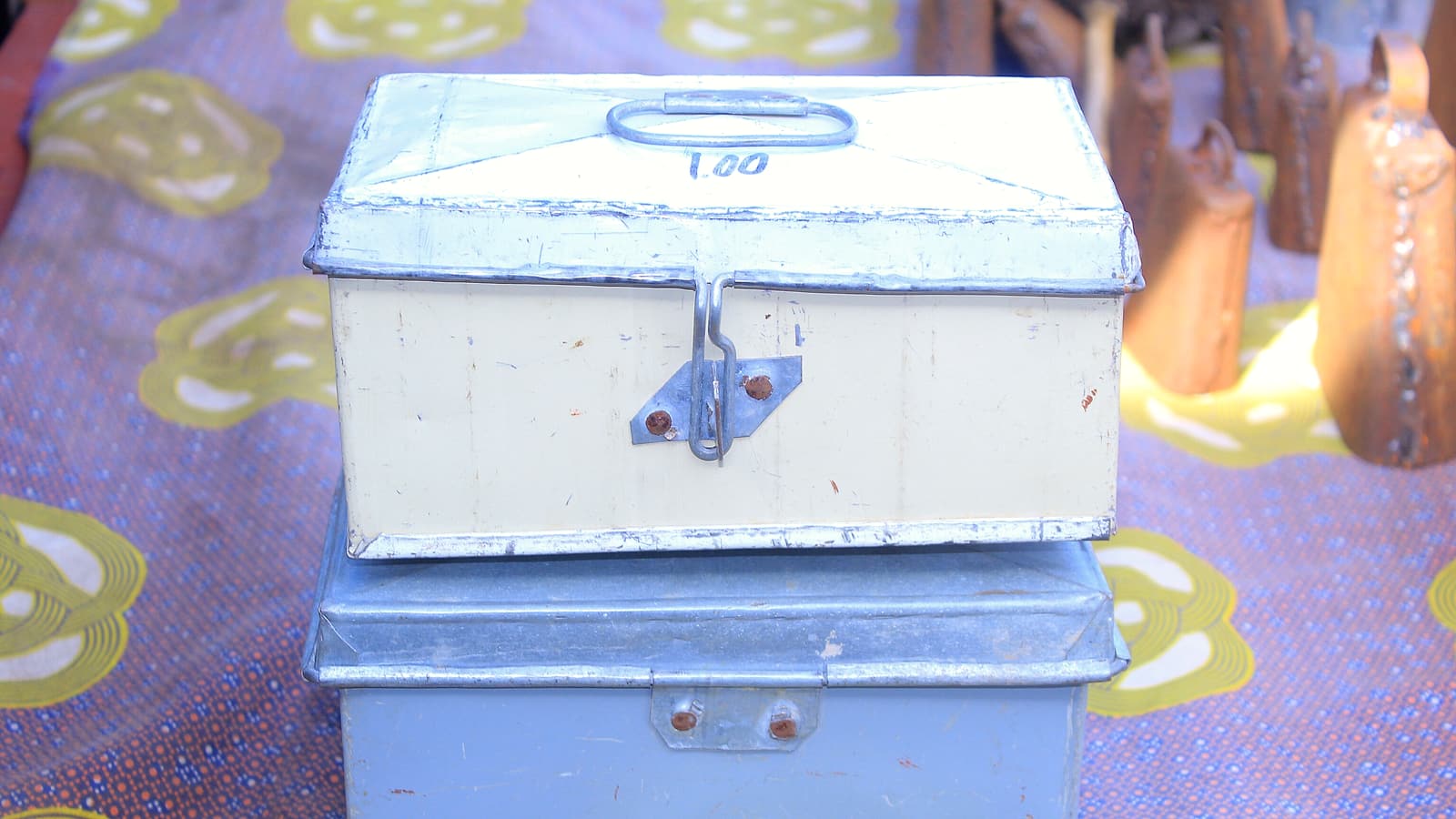 A closed metal cash box on a plain desk beside a receipt book and a stack of small paper slips