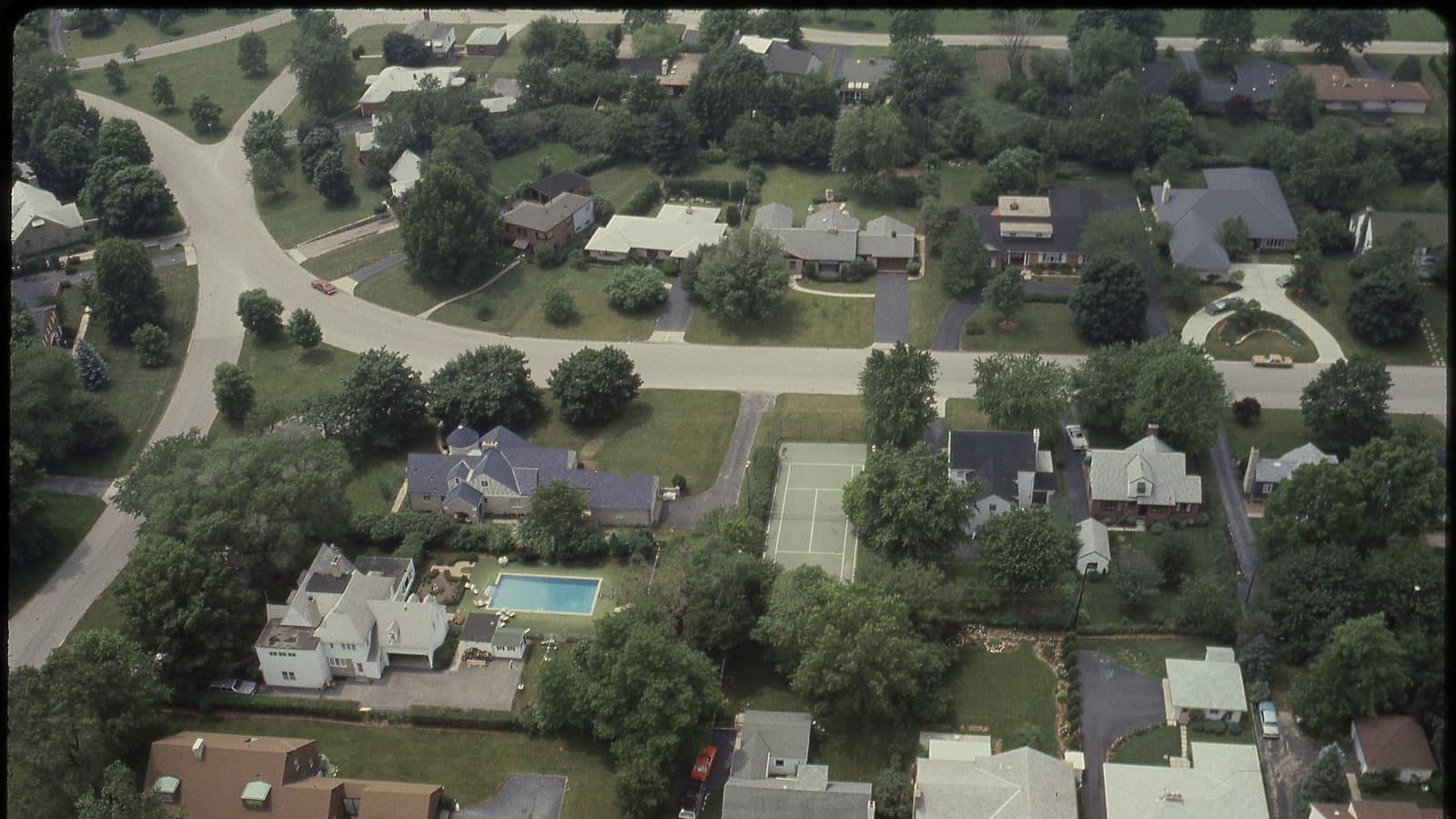 A row of similar suburban houses with identical mailboxes and trimmed front lawns along a quiet residential street